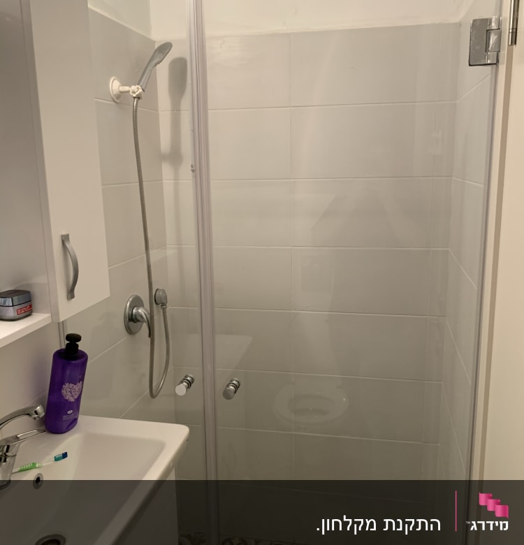 מקלחת עם דלת זכוכית וראש מקלחת כסוף